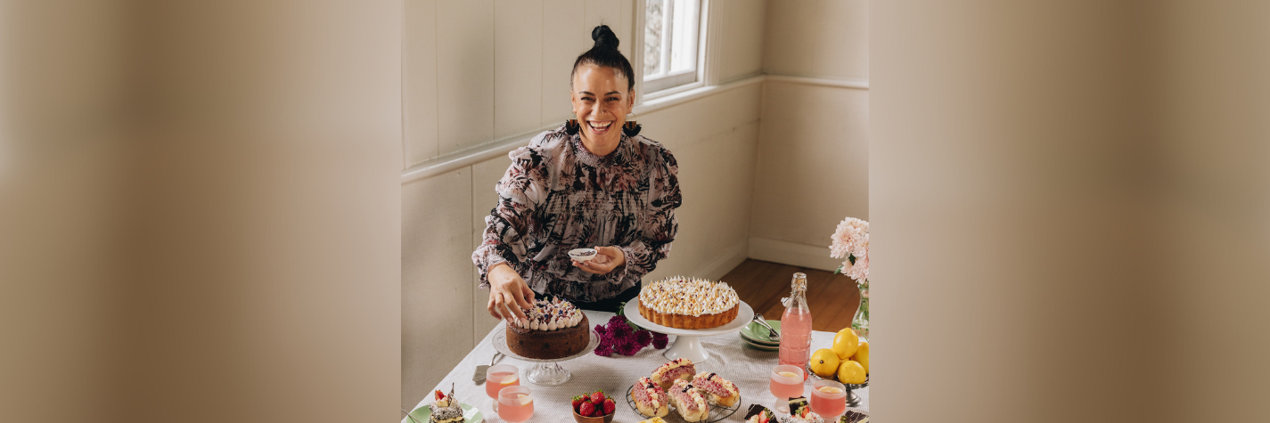 author naomi toilalo in front of a banquet of food